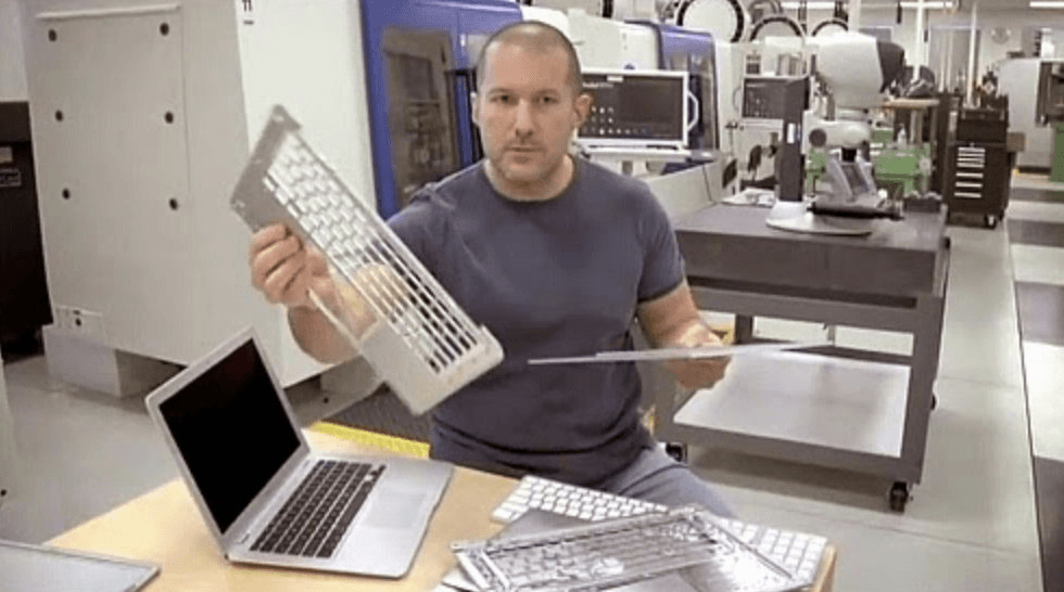 Jony Ive holding a translucent keyboard prototype in a workshop